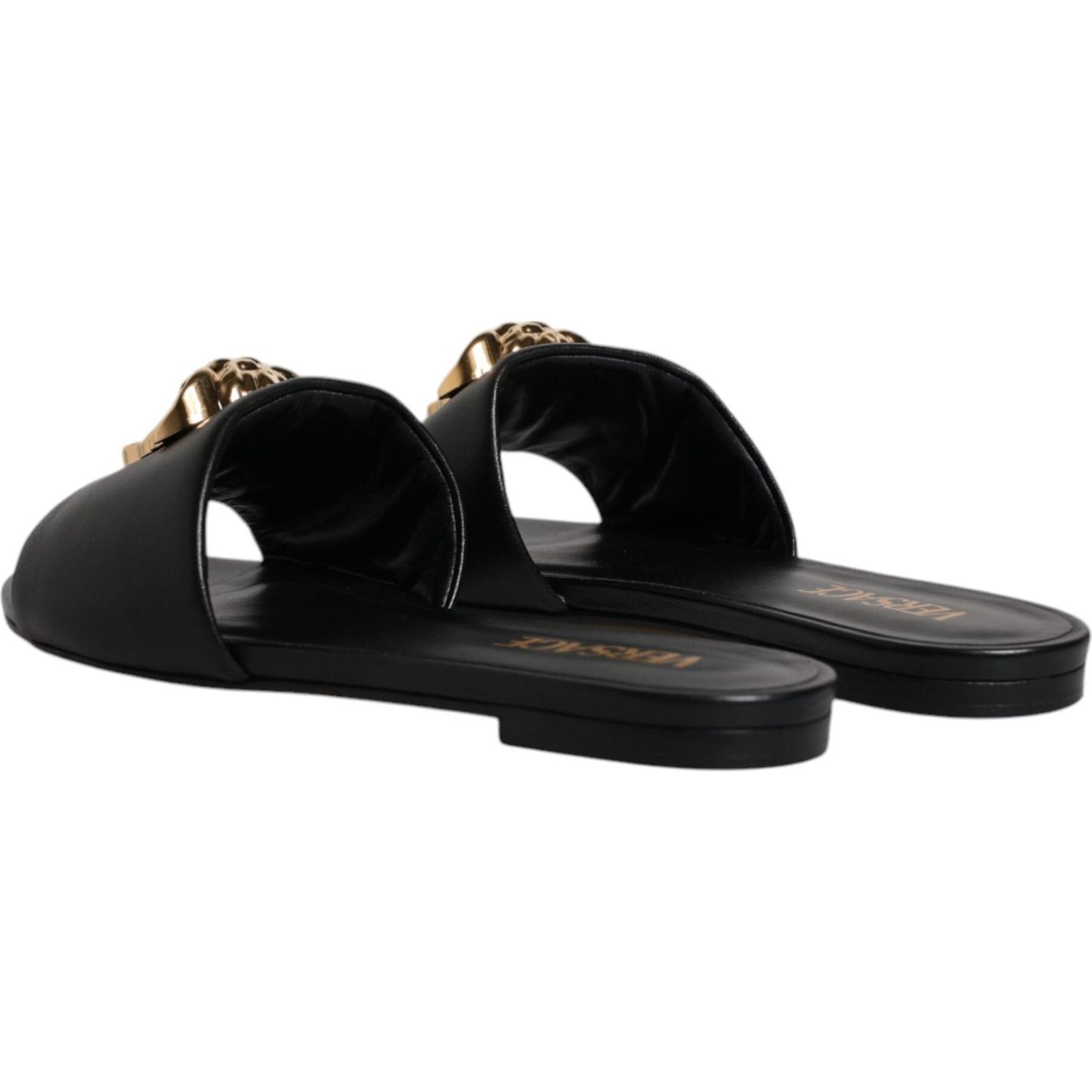 Versace black leather slip-on slides with gold logo plaque on toe, showcasing high-quality Italian craftsmanship.