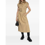 Model wearing tan dress and GANNI Boots Black with chunky lug sole and round toe, holding a small black bag.