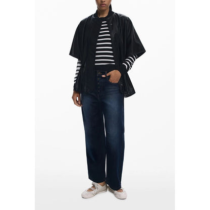 Model wearing Desigual Black Polyethylene Women Poncho with drawstring waist and embossed print, styled with striped top and jeans.