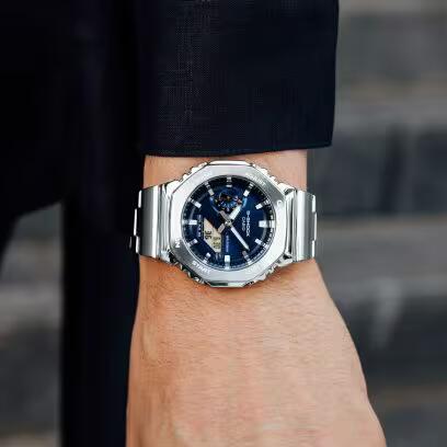 CASIO G-SHOCK Mod. OAK G-STEEL PETROL BLUE wristwatch worn on a man's wrist, featuring stainless steel bracelet and multifunction quartz movement.