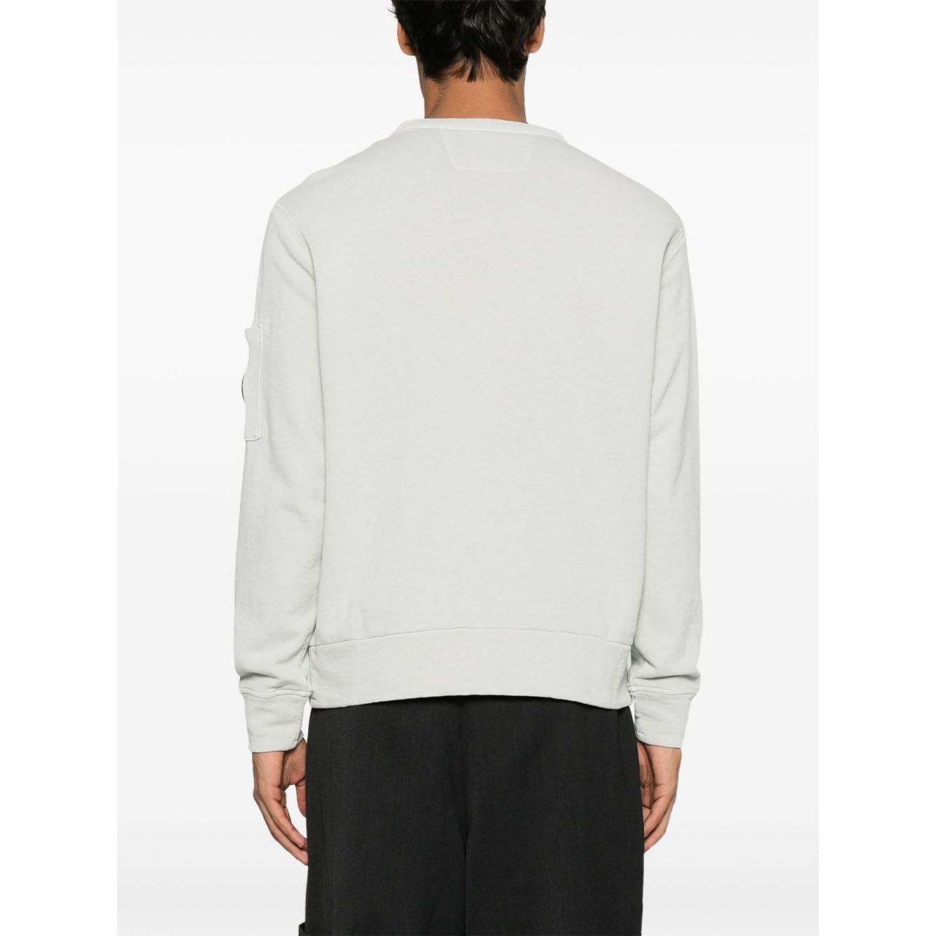 Back view of model wearing C.P. COMPANY Sweaters Clear Blue with ribbed cuffs and hem, sleeve patch pocket, and crew neck design.