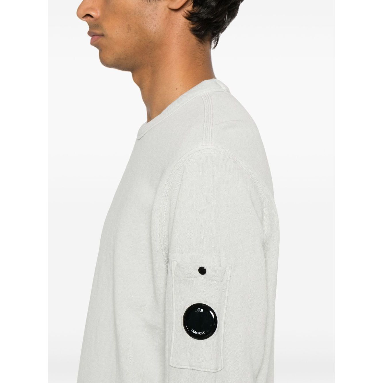 Side view of model in C.P. COMPANY Sweaters Clear Blue showing sleeve patch pocket and ribbed cuffs.