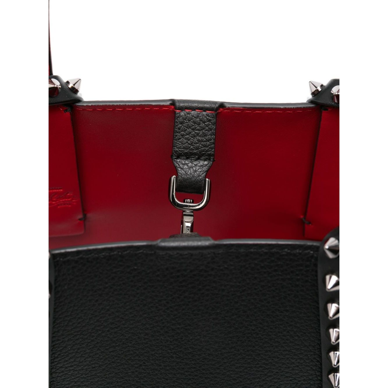 Interior of Christian Louboutin Cabata mini leather tote bag with red lining and spiked stud embellishment, showing clasp detail.