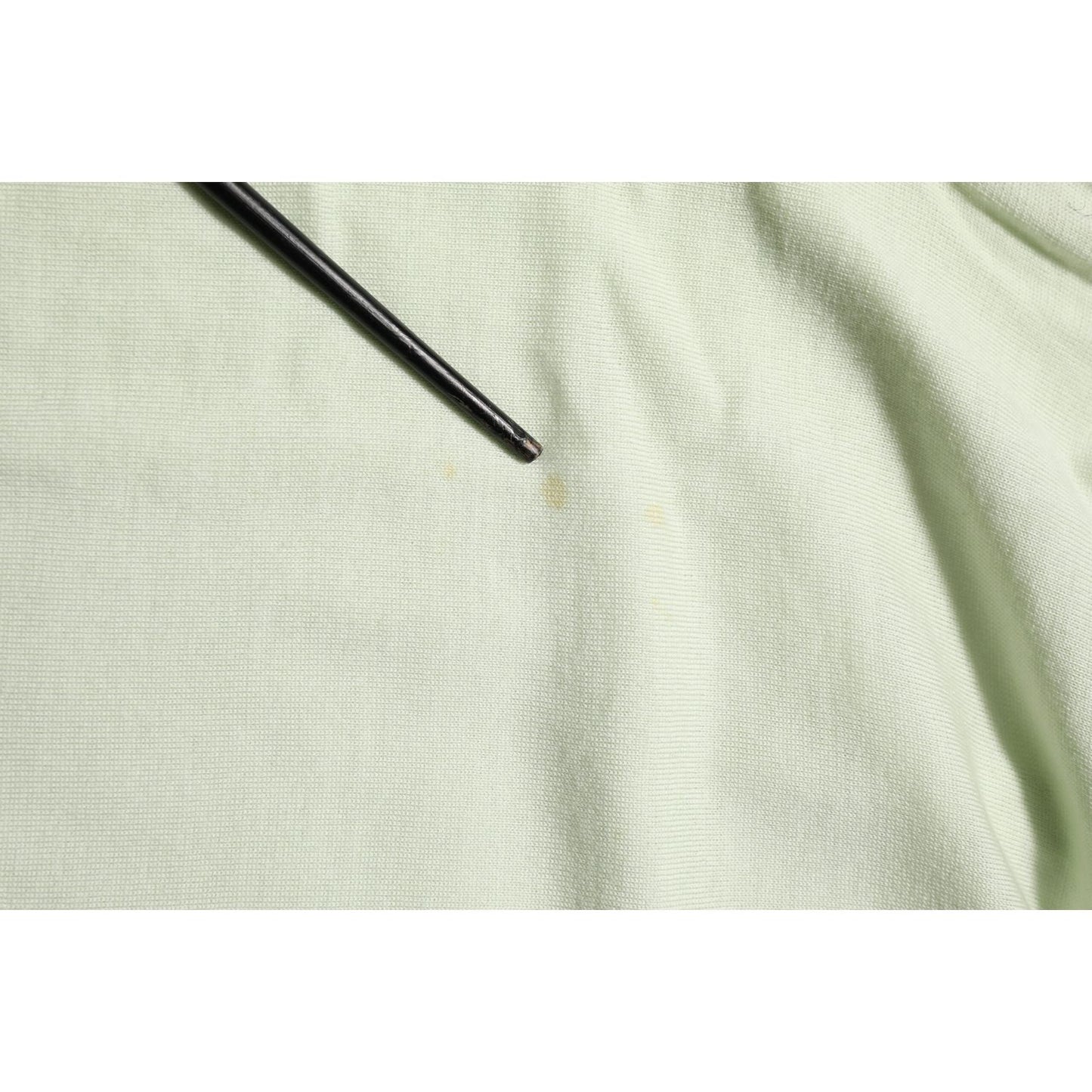 Close-up of Dolce & Gabbana Light Green Logo TurtleNeck Pullover Sweater fabric detail with a small mark