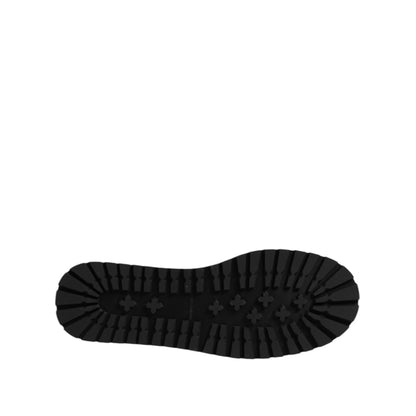 Bottom view of black boot sole with rugged tread design on solid background.