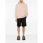 Model wearing blush pink Emporio Armani Sweaters Powder hoodie with drop shoulders and ribbed cuffs, paired with black shorts.