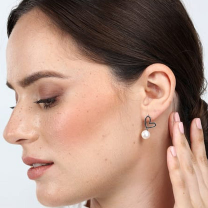 Woman wearing LA PETITE STORY JEWELRY Mod. LPS02AQM24 heart-shaped earrings with pearl drop.