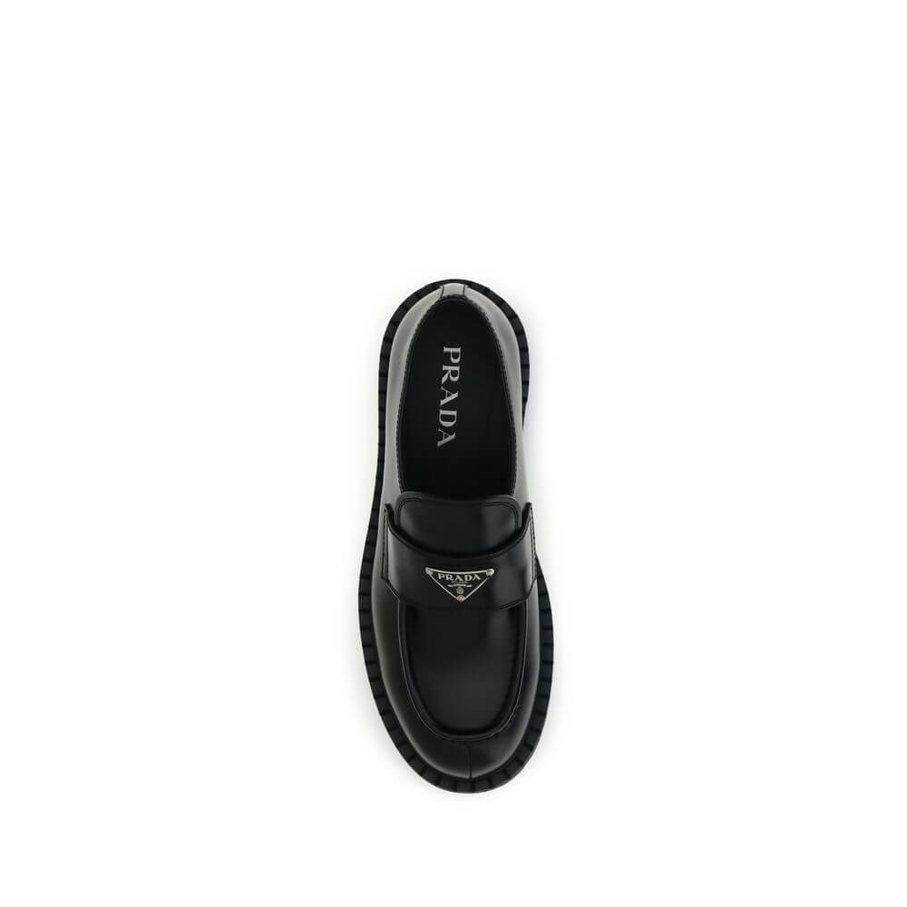 Prada Black Calf Leather Bos Taurus Slip-On Loafers with enameled triangle logo and rubber sole, top view.
