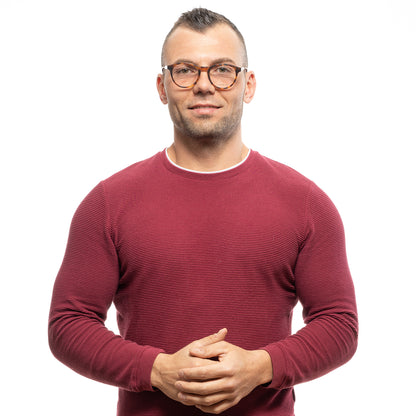 Man wearing a red sweater and glasses standing confidently.