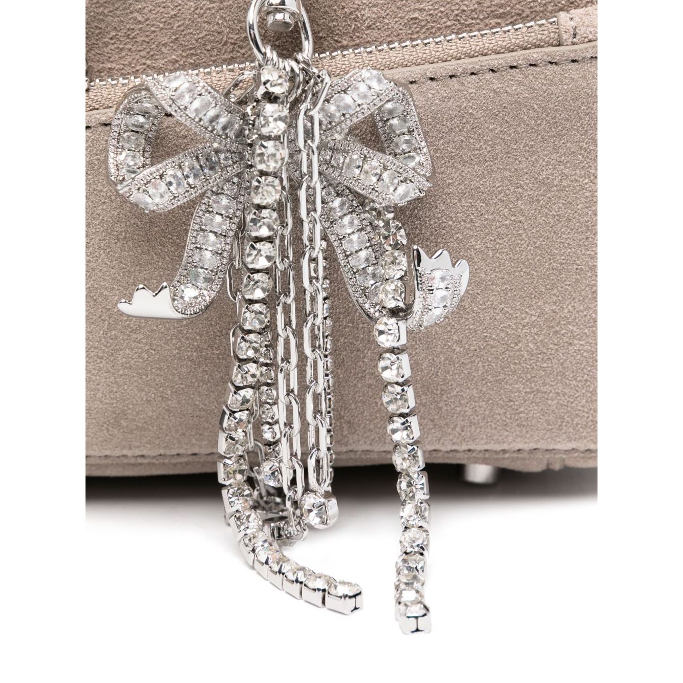 Close-up of silver-tone bow detailing on a grey suede shoulder bag with top zip fastening.