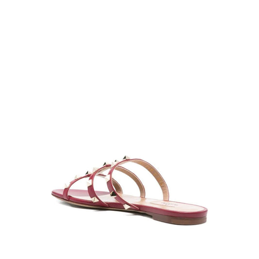 Valentino Garavani Rockstud three-strap sandals in red calf leather with flat sole and stud embellishments, open toe design, heel 1 cm.