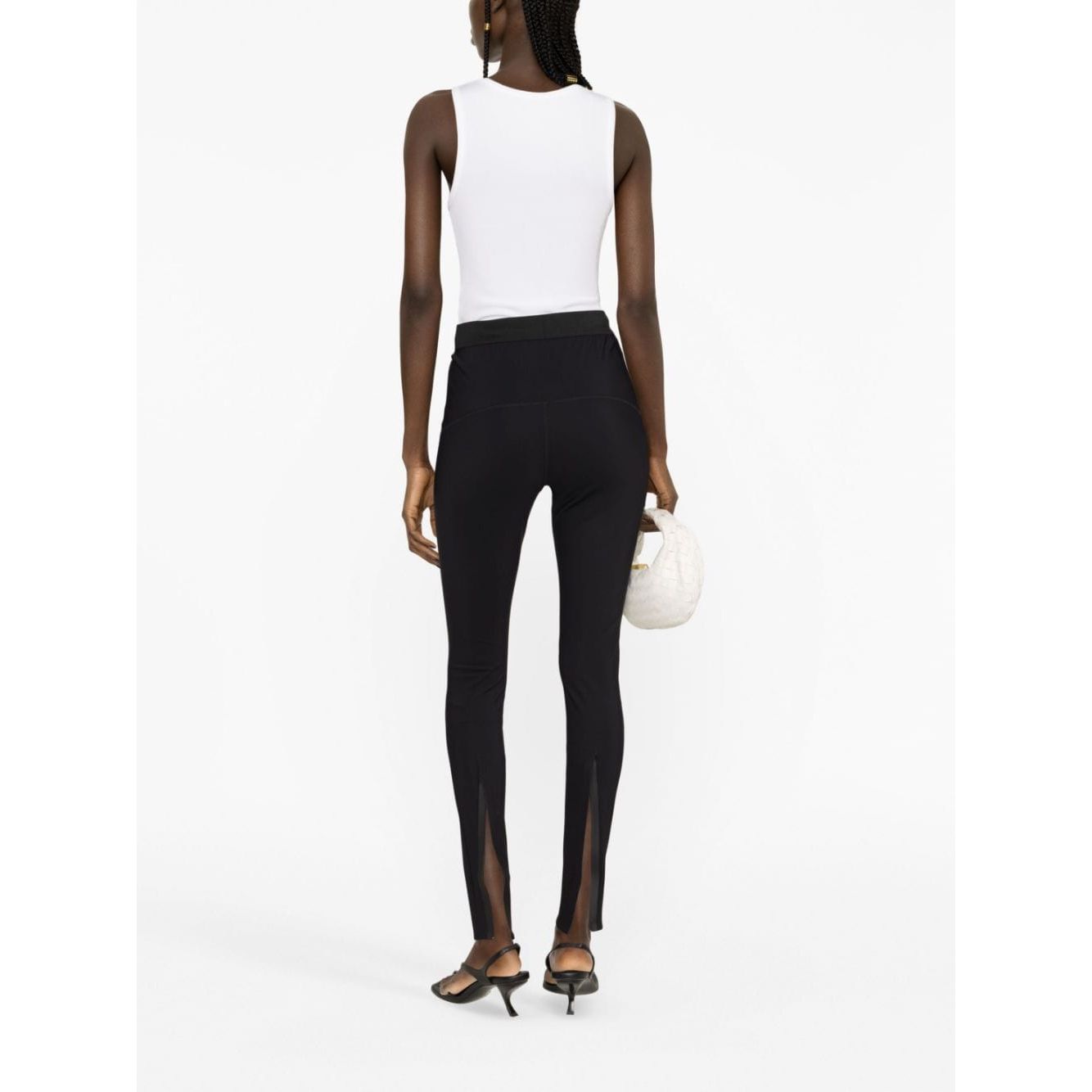 Woman wearing WARDROBE.NYC Trousers Black with elasticated waistband and rear slit, back view with white top and heels.
